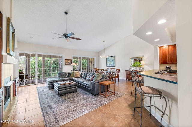 living room with vaulted ceiling, ceiling fan with notable chandelier, light tile patterned floors, and a textured ceiling