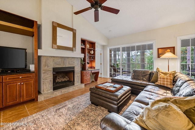 living room with a tile fireplace, ceiling fan, and high vaulted ceiling