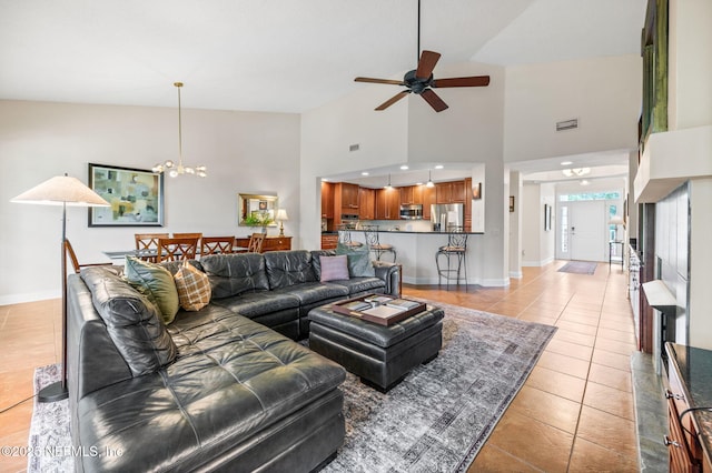 tiled living room with ceiling fan with notable chandelier and high vaulted ceiling