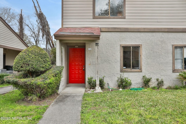 property entrance with a lawn and stucco siding