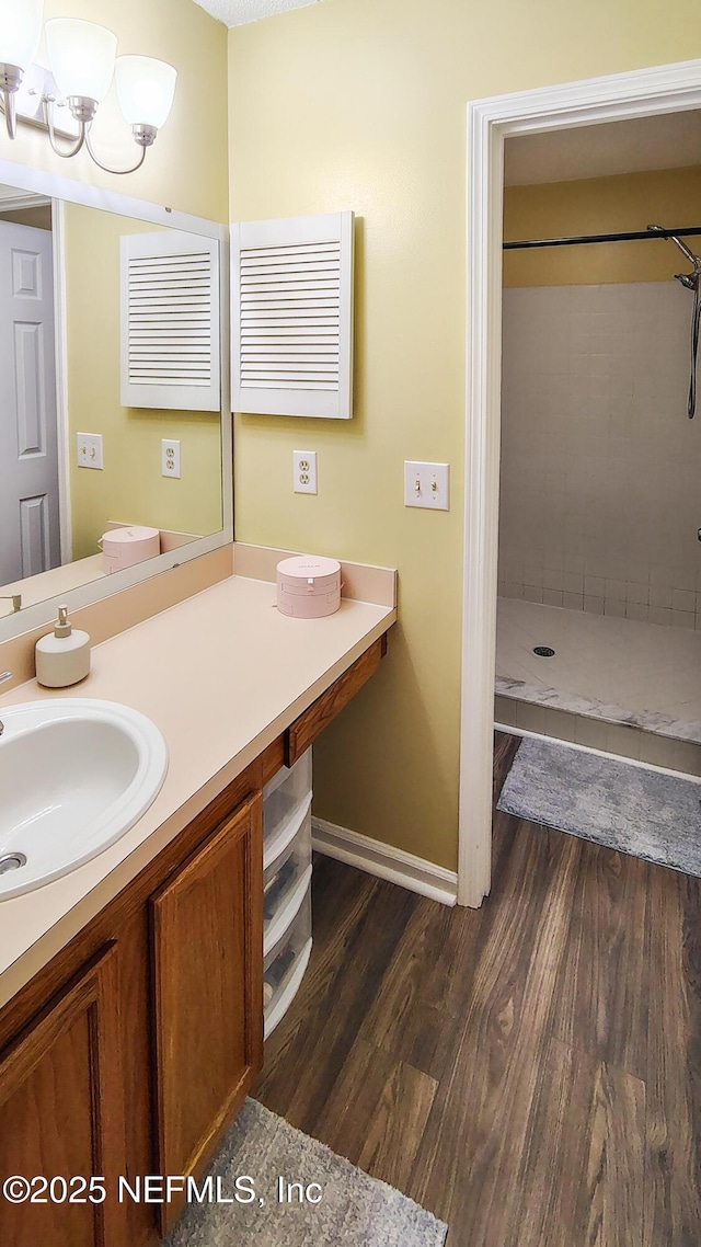 bathroom with vanity, tiled shower, and hardwood / wood-style floors