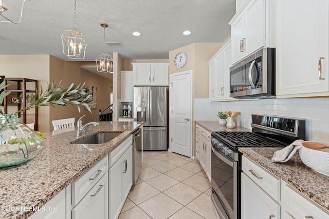 kitchen with light tile patterned floors, a sink, white cabinetry, appliances with stainless steel finishes, and backsplash