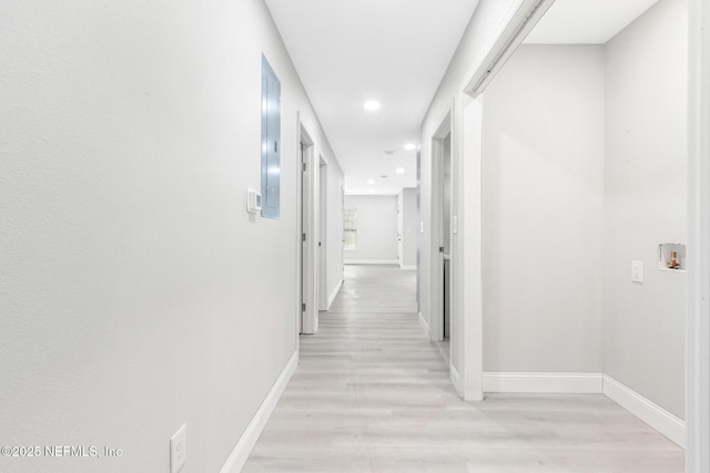 hall featuring baseboards, recessed lighting, and light wood-style floors