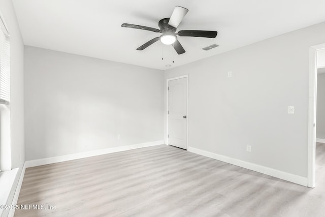 spare room featuring baseboards, visible vents, ceiling fan, and wood finished floors