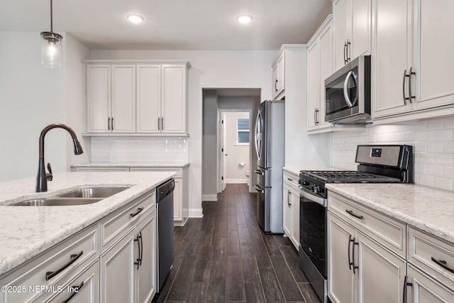 kitchen featuring stainless steel appliances, decorative light fixtures, light stone countertops, sink, and dark hardwood / wood-style floors