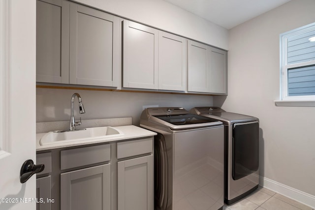 laundry area with light tile patterned flooring, cabinets, sink, and washer and clothes dryer