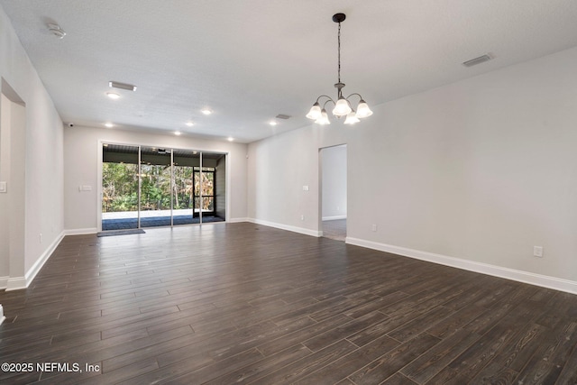 empty room featuring dark wood-type flooring and a chandelier