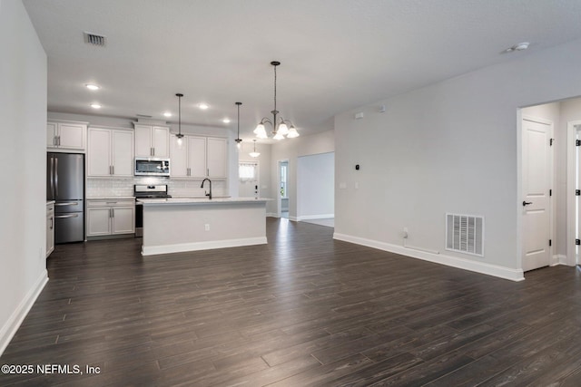 kitchen with sink, white cabinetry, pendant lighting, stainless steel appliances, and an island with sink