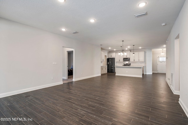 unfurnished living room featuring a textured ceiling, dark wood-type flooring, and a notable chandelier