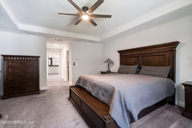 bedroom with a textured ceiling, light colored carpet, ceiling fan, and a raised ceiling