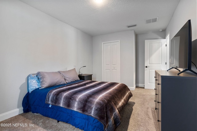 bedroom featuring light carpet, a closet, and a textured ceiling