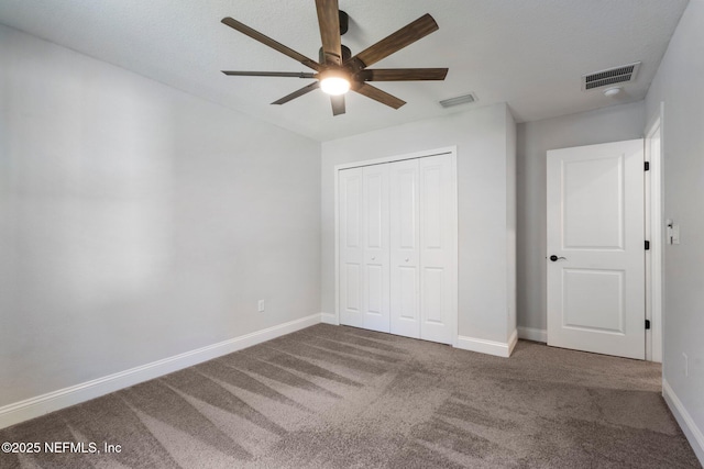 unfurnished bedroom featuring a closet, dark carpet, and ceiling fan