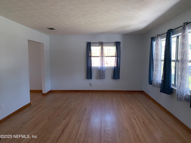 spare room with light hardwood / wood-style floors and a textured ceiling