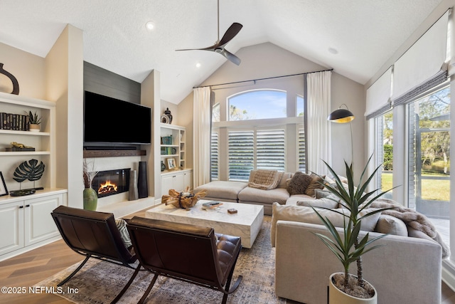 living area with light wood-style floors, a wealth of natural light, lofted ceiling, and a premium fireplace