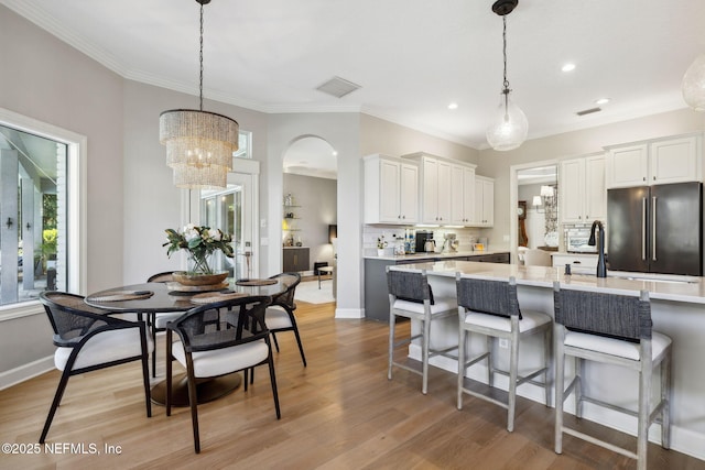 kitchen featuring light wood finished floors, white cabinets, high end fridge, hanging light fixtures, and backsplash