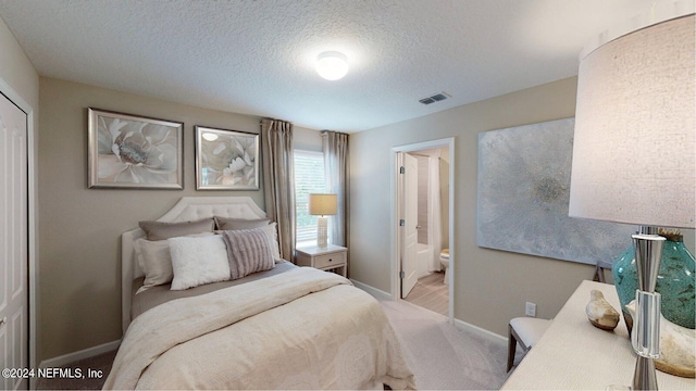 bedroom with light colored carpet, ensuite bath, and a textured ceiling