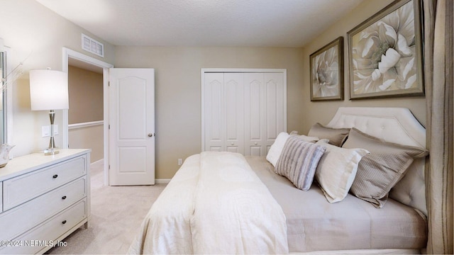 bedroom with light carpet, a textured ceiling, and a closet