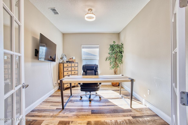 office space with a textured ceiling and light hardwood / wood-style flooring