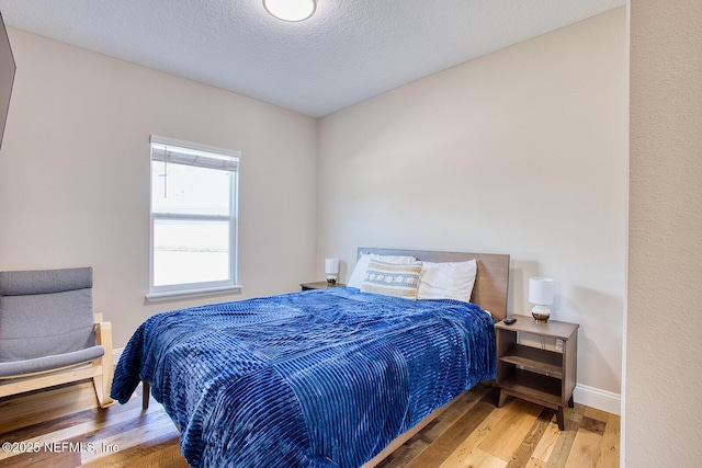 bedroom with hardwood / wood-style floors and a textured ceiling