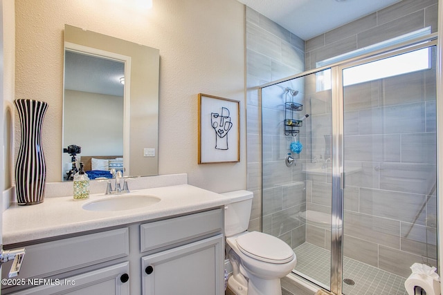 bathroom featuring vanity, toilet, and a shower with door