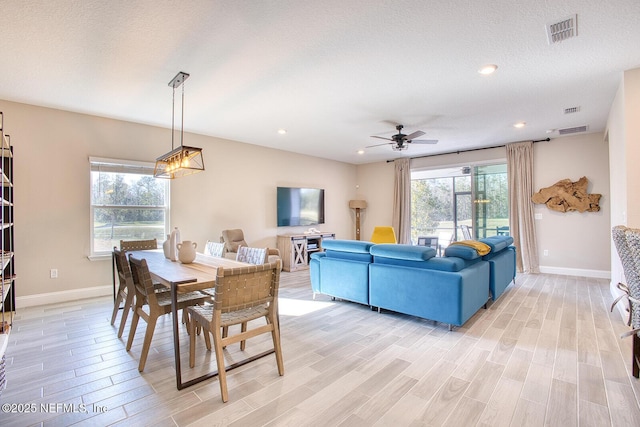 dining space featuring ceiling fan, a textured ceiling, and light wood-type flooring