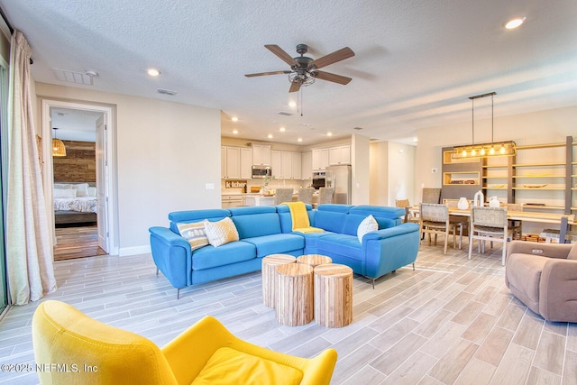 living room featuring a textured ceiling and ceiling fan