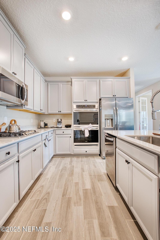 kitchen with white cabinetry, sink, a textured ceiling, and appliances with stainless steel finishes