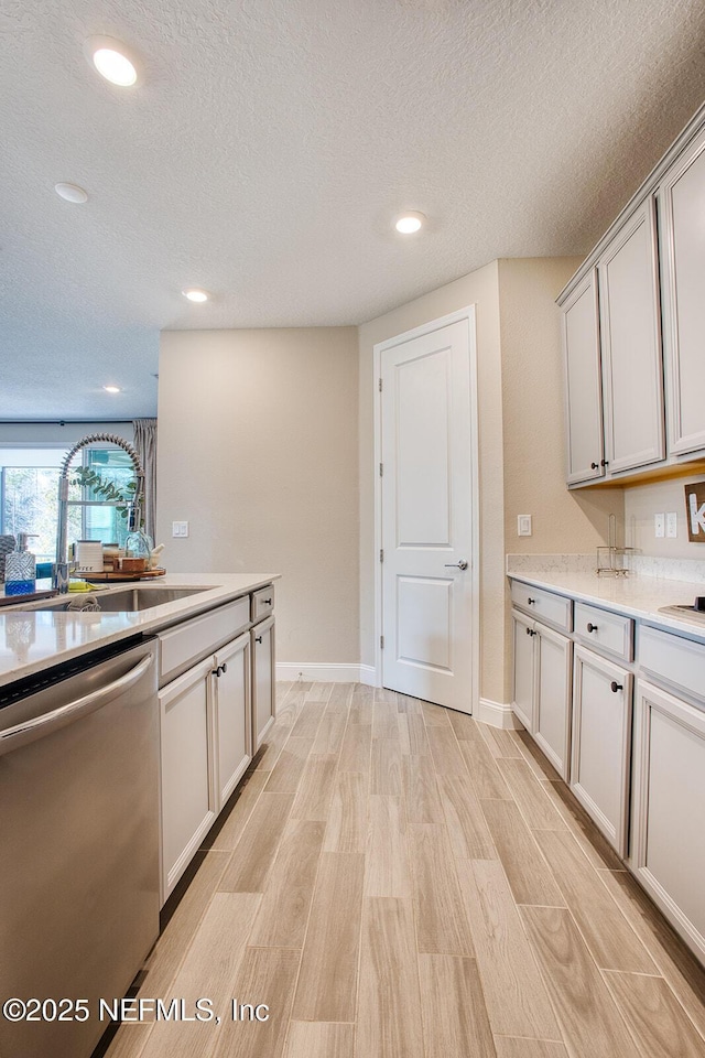 kitchen featuring sink, a textured ceiling, light hardwood / wood-style floors, and dishwasher