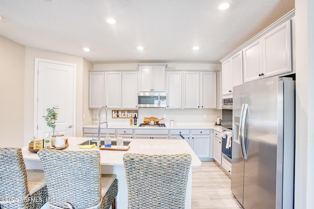 kitchen featuring sink, stainless steel appliances, a kitchen breakfast bar, and a center island with sink