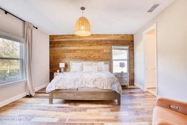 unfurnished bedroom with hardwood / wood-style flooring and wood walls