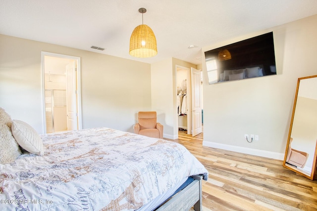 bedroom with connected bathroom, a spacious closet, and hardwood / wood-style floors