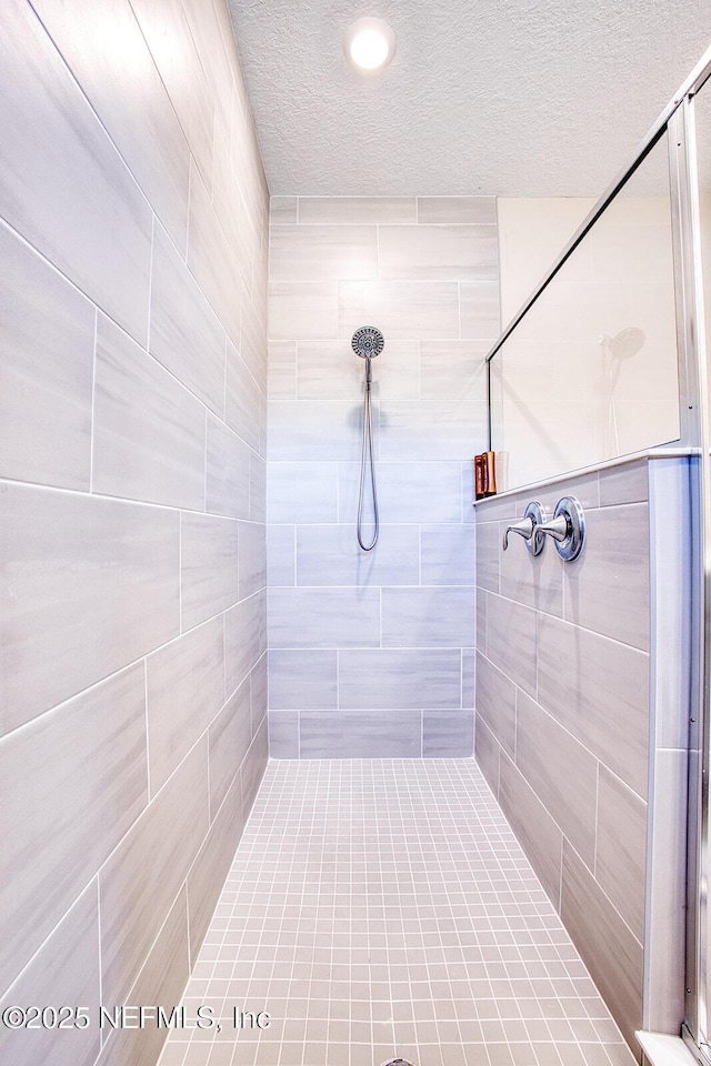 bathroom featuring tiled shower and a textured ceiling