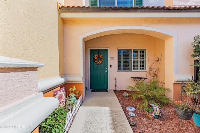 property entrance with a tile roof and stucco siding