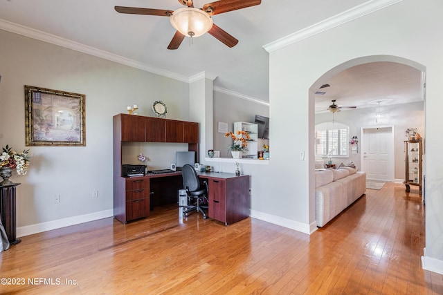 office area with arched walkways, a ceiling fan, baseboards, light wood-style floors, and crown molding