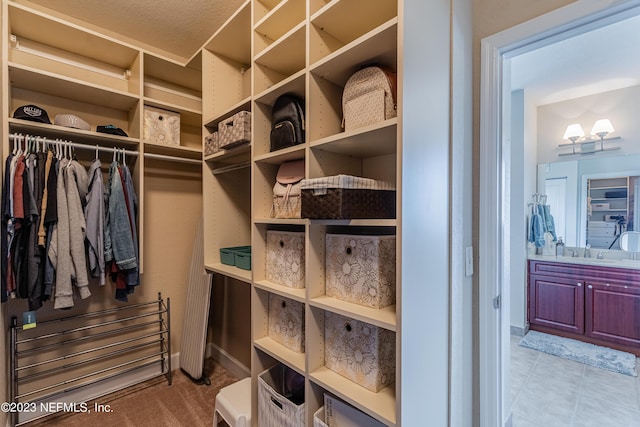 walk in closet with light tile patterned floors and a sink