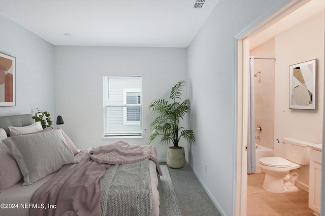 bedroom with ensuite bath and light hardwood / wood-style flooring