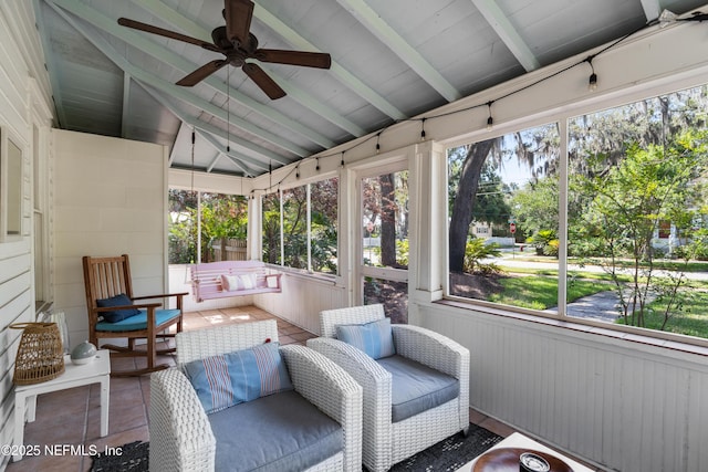 sunroom with lofted ceiling with beams, a healthy amount of sunlight, and ceiling fan