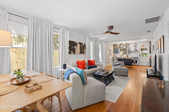 living room featuring ceiling fan, a wealth of natural light, and light hardwood / wood-style floors