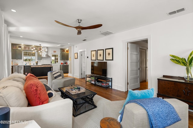 living room with dark wood-type flooring and ceiling fan with notable chandelier