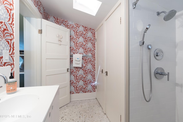 bathroom featuring tile patterned floors, vanity, a skylight, and a tile shower