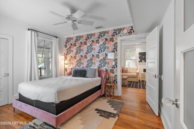 bedroom with multiple windows, ornamental molding, ceiling fan, and light wood-type flooring