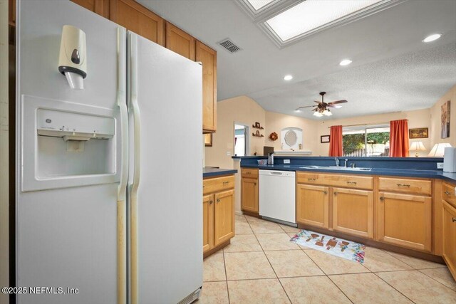 kitchen with sink, white appliances, ceiling fan, a skylight, and light tile patterned flooring