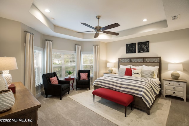 carpeted bedroom featuring ceiling fan and a raised ceiling