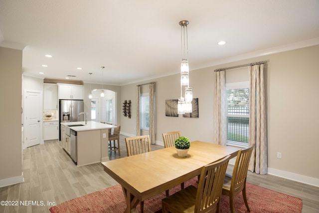 dining room featuring sink, crown molding, and light wood-type flooring