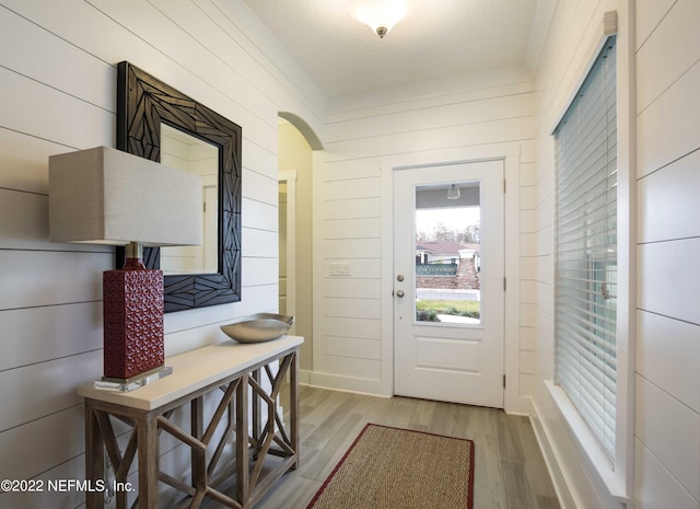 doorway to outside with wooden walls and light hardwood / wood-style floors