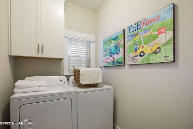 clothes washing area featuring washer and clothes dryer and cabinets