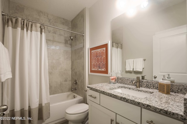 full bathroom featuring vanity, shower / tub combo with curtain, a textured ceiling, and toilet