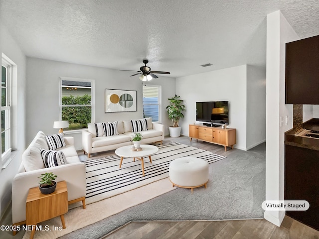 living room with hardwood / wood-style flooring, ceiling fan, and a textured ceiling