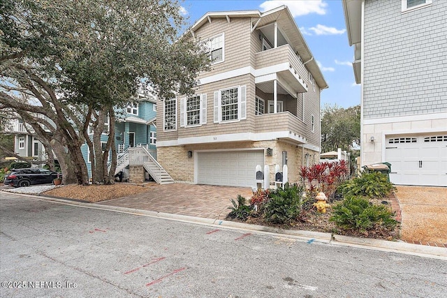 view of front of property featuring a garage, stairs, and decorative driveway