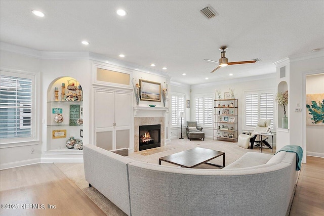 living room featuring a lit fireplace, visible vents, and crown molding